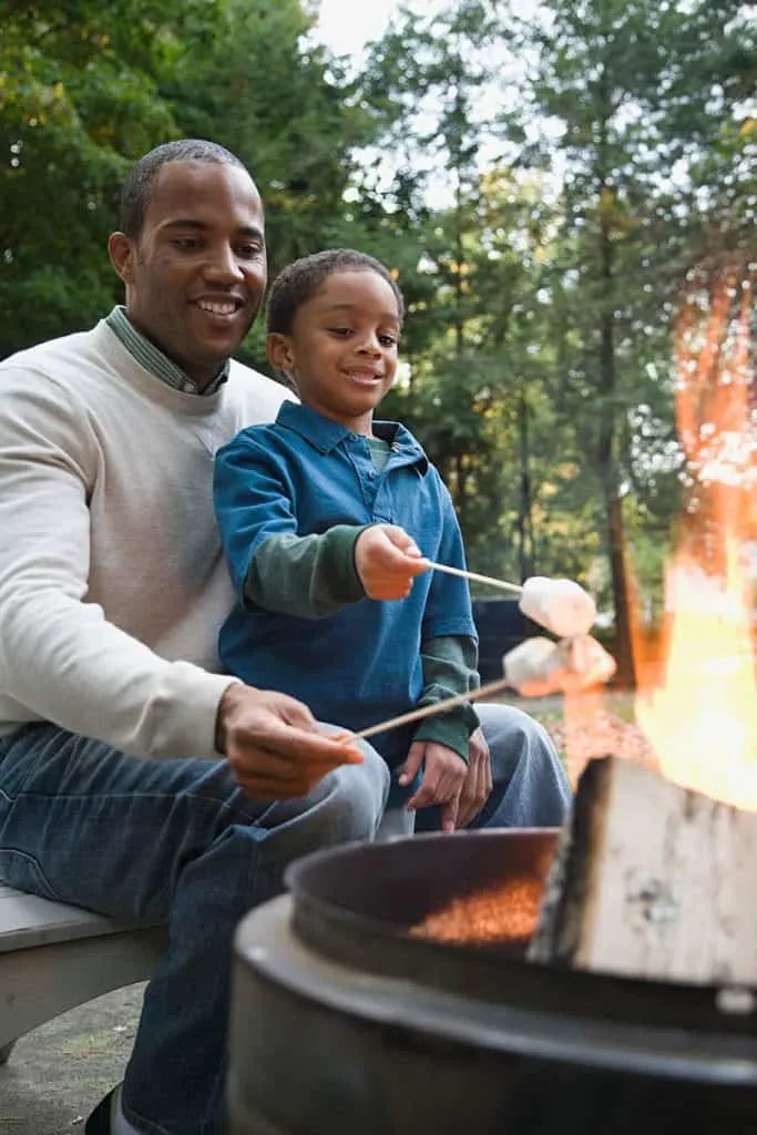 father helping son safely make s'mores