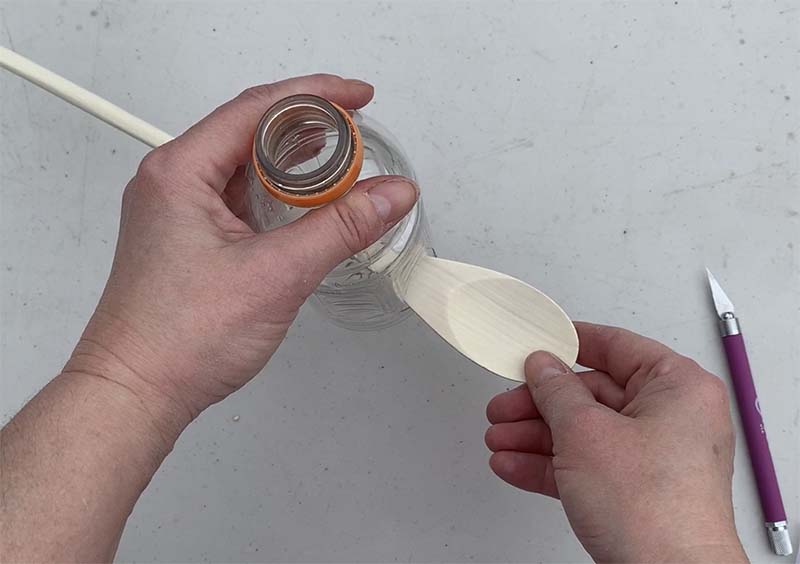 slide spoon into hole in plastic bottle